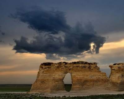 [Dragon-shaped cloud over a rock arch]