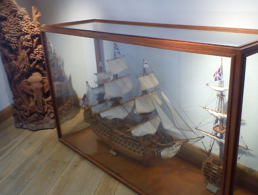 Large class case containing model ship, with carved elephants standing behind it